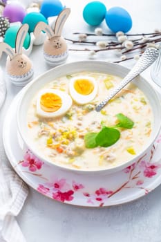 Homemade polish Easter soup with addition of sausage, hard boiled egg and vegetables in a bowl
