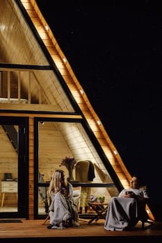 Calm conversation between man and woman on the terrace of a-frame cabin in the evening
