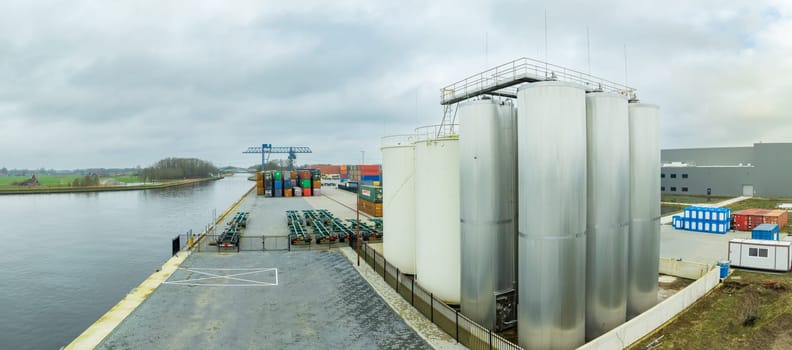 aerial shot of some shiny industrial silos along a canal