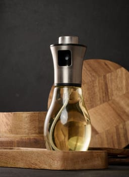 Glass transparent spray bottle filled with sunflower oil on a black table