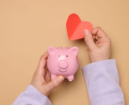Ceramic piggy bank and red paper heart, concept of collecting love and goodness