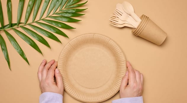 Paper plates and cups on a beige background, top view