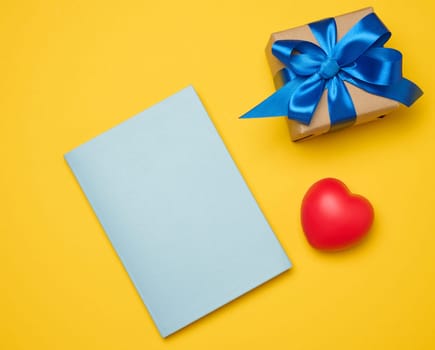 Notepad and gift box on yellow background, top view