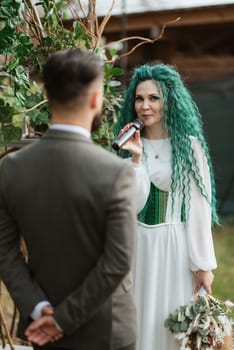 wedding ceremony of the newlyweds in a country cottage on a green hill