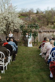 wedding ceremony of the newlyweds in a country cottage on a green hill