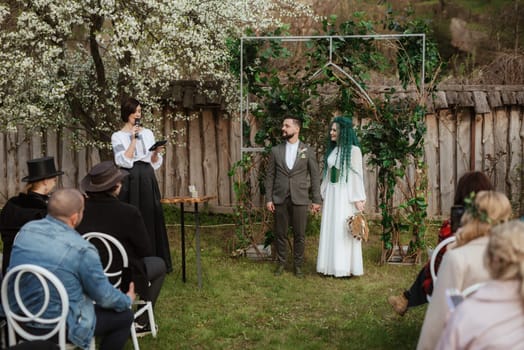 wedding ceremony of the newlyweds in a country cottage on a green hill