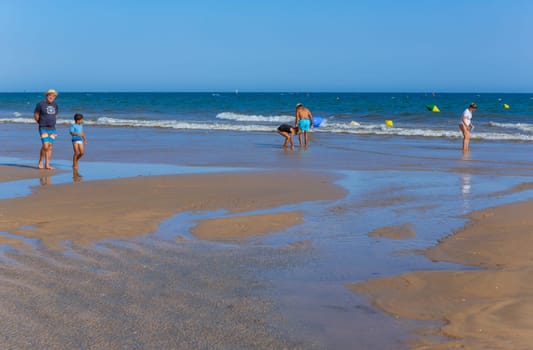Tavira, Portugal - August 15, 2023: People at the famous beach of Tavira island in Tavira. This beach is a part of famous tourist region of Algarve.