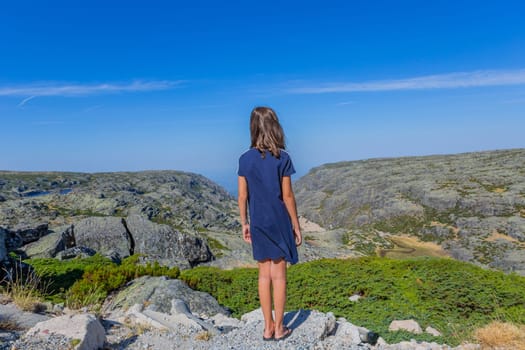 Girl tourist standing overlooking at picturesque view of the mountain, in Serra da Estrela, Portugal. View from behind