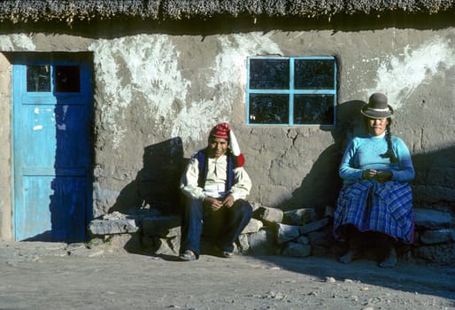 Taquile, Peru - February 7, 1985: local couple dressed in traditional farmers clothes rests in front of her rural hut at island Taquile in lake Titicaca.