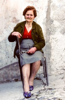 POSITANO, ITALY - JUNE 30, 1995: old woman in Positano sits in front of her house and enjoys posing for photo.