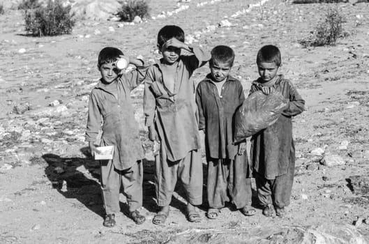 Gilgit, Pakistan - July 6, 1987: poor children in dirty local clothes pose in   dusty landscape at the Karakoram Hwy near Gilgit, Pakistan. Education for the tribal people is very poor in that area.