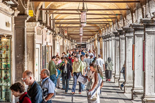 Venice, Italy - September 23, 2005: people enjoy walking along the collonades at San Marco square in Venice, Italy.
