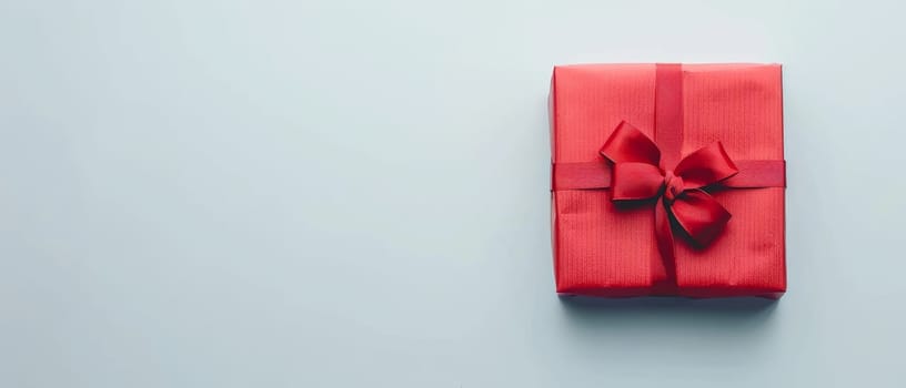A minimalist red gift box with a neatly tied bow stands out on a pristine white background, symbolizing elegance and thoughtful giving. Its crisp presentation suggests a modern twist to gift-giving