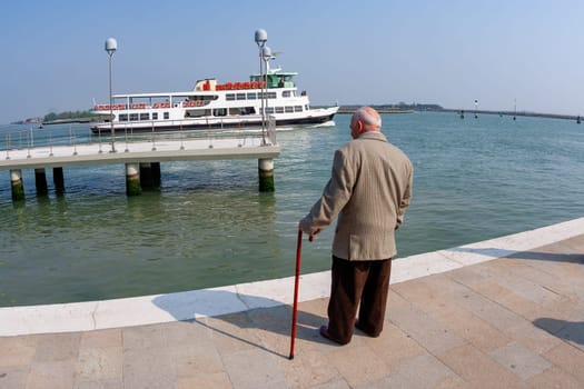 Venice, Italy - April 10, 2007: old man with walking stick waits for the ferry in Venice, Italy.