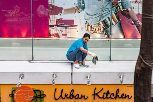 Bangkok, Thailand - December 27, 2007: women cleans the shopping window and facade of an expensive shopping mall downtown Bangkok.