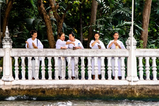 Bangkok, Thailand - December 26, 2007: nuns in white clothes throw blossons into the river to honor the godness.