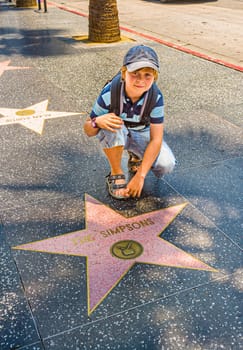 Los Angeles, USA - July 5, 2008: boy at the  Walk of Fame poses at the star for The simpsons.