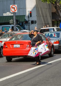 San Francisco, USA - July 24, 2008: woman with fully filled shopping bag crosses a street downtown San Francisco after shopping.