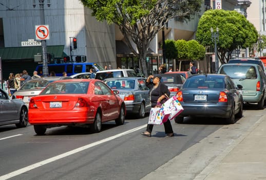 San Francisco, USA - July 24, 2008: woman with fully filled shopping bag crosses a street downtown San Francisco after shopping.