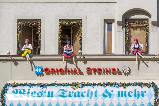 Munich, Germany - April 7, 2009: puppets in bavarian costumes sitting at the window with advertising for original bavarian custumes.