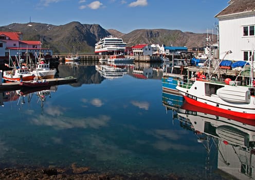 Hurtigrouten, Norway - July 9, 2009: small harbor at a norwegian coastal village with Hurtigrouten harbor stop and reflection in harbor of fishermens boats.