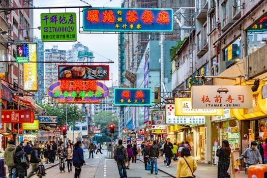 Hongkong, China - January 7, 2010: shopping street in late afternoon with illuminated shops and people hurry around in downtown Hongkong, Kowloon.