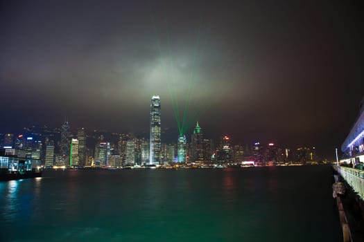 Kowloon, Hongkong - January 7, 2010: Hong Kong skyline at night with lights and skyscrapers over sea with laser beams
