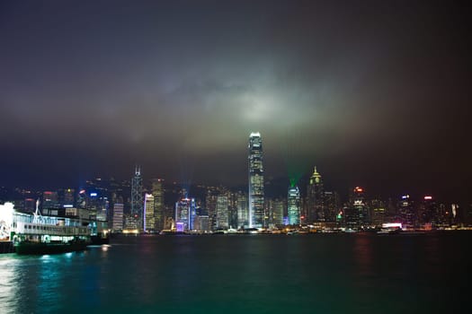 Kowloon, Hongkong - January 7, 2010: Hong Kong skyline at night with lights and skyscrapers over sea with laser beams