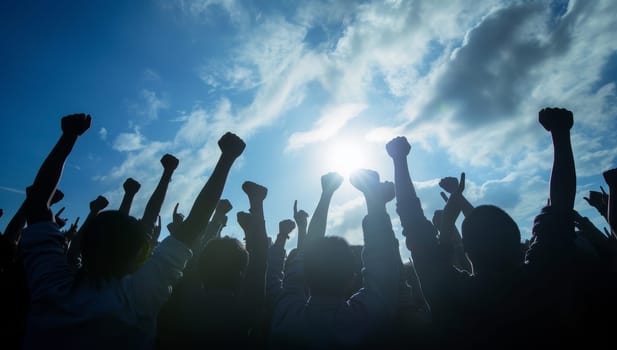 Silhouette of a group of people raising their hands in the air