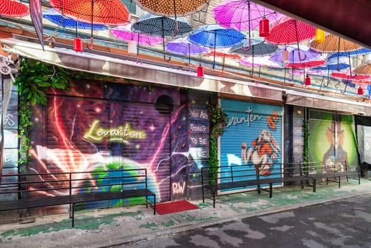 Istanbul, Turkey - May 13, 2023: Vibrant canopy of colorful umbrellas hangs suspended above an alley in Karakoy, in an eye catching installation that creates a whimsical and playful atmosphere