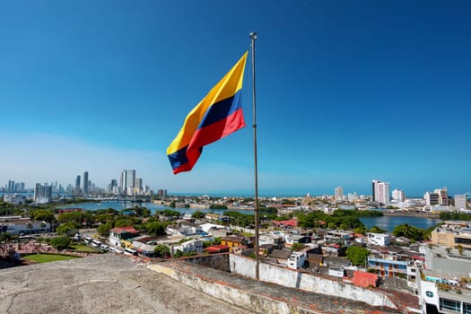 Urban skyline of Cartagena de Indias city on the Caribbean coast of Colombia. In front colombian flag. View from fortress San Felipe de Barajas Fort.