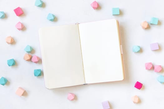 Opened hardcover notebook near pastel geometric decor on white table top view. Textbook mockup. Back to school concept mockup, planner cover with place fot text. Educational and girly concept