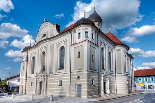 Nesselwang, Germany - July 06, 2023: Wide angle corner view of the Saint Andreas Church in Nesselwang from the south-west against a blue sky with white clouds.