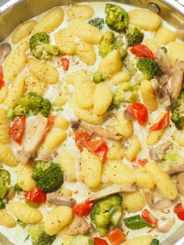 Delicious, hearty gnocchi dish in a pan with various vegetables, vegetarian traditional home cooking
