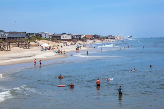 Nags Head, USA - July 18, 2010: people enjoy bathing in Nags Head, USA. Established in the 1830s as first tourist colony. The first oceanfront cottage was built here around 1855 by Dr. W.G. Pool.