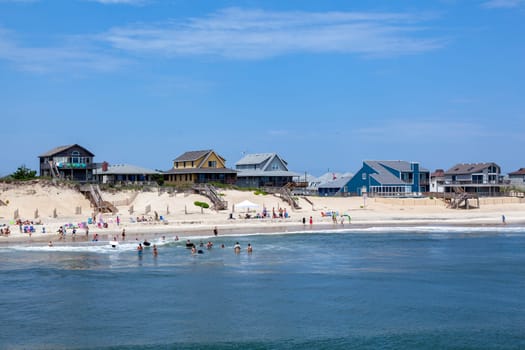 Nags Head, USA - July 18, 2010: people enjoy bathing in Nags Head, USA. Established in the 1830s as first tourist colony. The first oceanfront cottage was built here around 1855 by Dr. W.G. Pool.