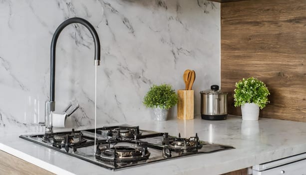 Contemporary kitchen with white countertop, gas stove, and sink.