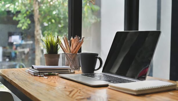 Modern workplace with laptop computer, coffee cup and office supplies