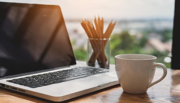 Modern workplace with laptop computer, coffee cup and office supplies