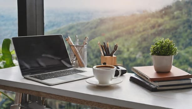 Modern workplace with laptop computer, coffee cup and office supplies