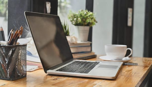 Modern workplace with laptop computer, coffee cup and office supplies