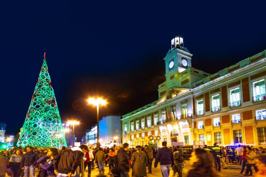 Madrid, Spain - December 22, 2010:  People have fun in Christmas time passing the famous illuminated christmas tree at puerta del sol in Madrid, Spain.