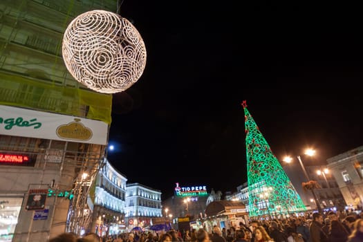 Madrid, Spain - December 22, 2010:  People have fun in Christmas time passing the famous illuminated christmas tree at puerta del sol in Madrid, Spain.