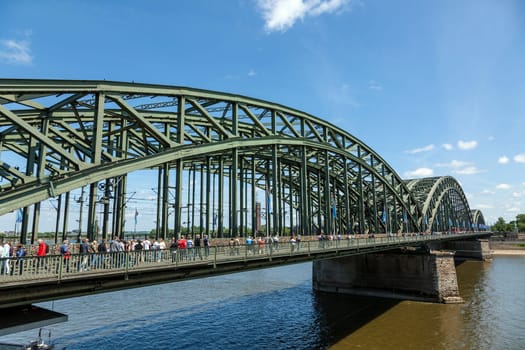 Cologne, Germany - May 29, 2011: people enjoy to walk along the promenade at the Hohenzollern bridge in Cologne, Germany. It is the most heavily used railway bridge in Germany.