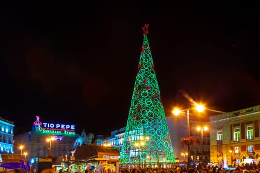 Madrid, Spain - December 22, 2010:  People have fun in Christmas time passing the famous illuminated christmas tree at puerta del sol in Madrid, Spain.