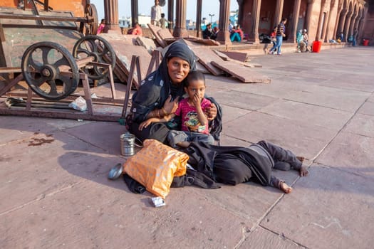 Delhi, India - November 10, 2011: mother with child rests on the courtyard of Jama Masjid Mosque in Delhi. Jama Masjid is the principal mosque of Old Delhi in India.