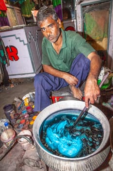 Jaipur, India - November 11, 2011: unidentified dyer works at outdoor factory  in Jaipur, India. He dyes clothes with colors.