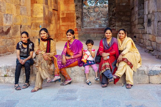 New Delhi, India - November 13, 2011:  indian tourists in colorful festival dress visit the minaret Qutub Minar in New Delhi, the worlds tallest brick minaret with 72 meters.