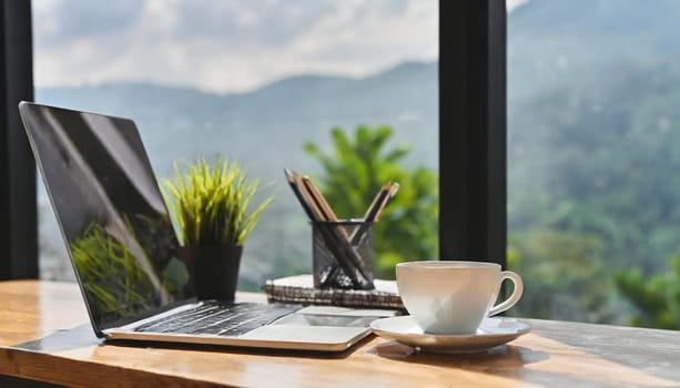 Modern workplace with laptop computer, coffee cup and office supplies