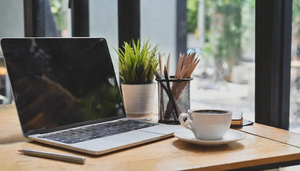 Modern workplace with laptop computer, coffee cup and office supplies